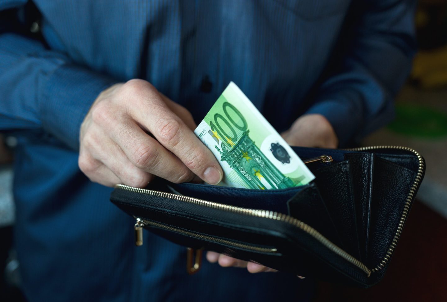 A man's hand takes money from his wallet putting money